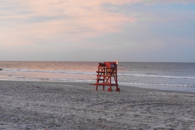 白天海滩上的红色木制救生椅